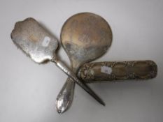 A silver backed hand mirror and two brushes