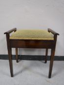 A mahogany storage piano stool containing sheet music