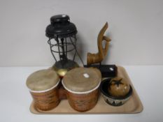 A tray containing a paraffin lamp, hand drums, wooden maracas,