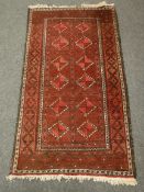 A fringed Afghan rug on red ground,