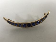 A 9ct gold crescent shaped brooch set with sapphires, 3.1g.
