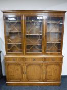 A yew wood triple door bookcase fitted cupboards and drawer beneath