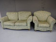 A two seater settee and armchair, upholstered in a green and gold fabric,