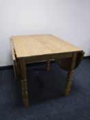A blonde oak drop leaf dining table