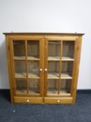 A pine glazed double door wall cabinet,