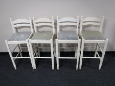 A set of four white bar stools