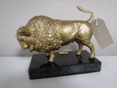 A gilt metal figure of a bison on a marble base
