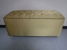 A large blanket box upholstered in a gold button fabric