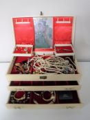 A cream leatherette jewellery box containing assorted costume jewellery, simulated pearls,