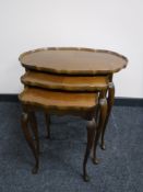 A nest of three walnut pie crust edge tables