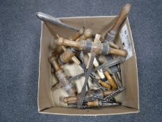 A box containing antique woodworking tools, including chisels, drill bits,