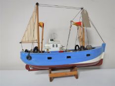 A wooden model of a fishing trawler on stand