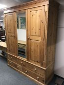 A pine triple door wardrobe fitted with drawers,
