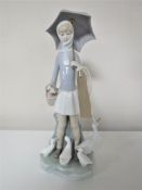 A Lladro figure of a girl holding an umbrella surrounded by ducks