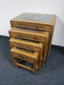 A nest of four carved oriental glass topped tables