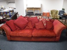 A three seater settee upholstered in a red fabric,