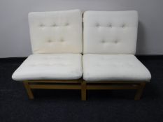 A contemporary two seater settee upholstered in a cream button fabric