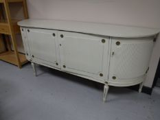 A white and gilt four drawer D-shaped sideboard on reeded legs