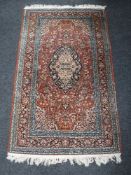 A fringed Eastern rug on red ground