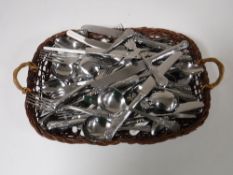 A basket containing stainless steel table cutlery