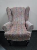 A wing back armchair upholstered in a pink floral fabric