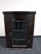 An antique oak hanging corner cupboard with glazed door