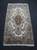 A fringed woolen floral rug on cream ground