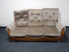 A mid 20th century teak framed saddle suite in brown fabric