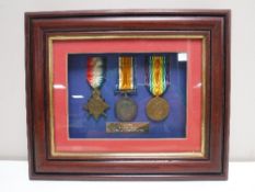 A framed set of three WWI medals presented to John Simm of Durham Light Infantry