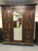 An Edwardian oak triple door mirrored wardrobe,
