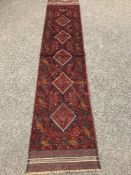 A Persian carpet runner on red ground,