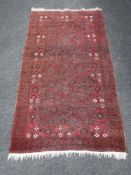 A fringed woolen Persian rug on red ground