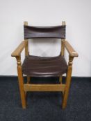 An antique oak armchair upholstered in brown button leather
