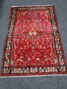 A fringed Turkish woolen rug on red ground