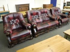 A wood framed burgandy button leather three piece lounge suite