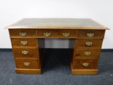 An Edwardian oak twin pedestal desk with green leather inset panel