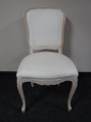 A contemporary French style bedroom chair, upholstered in a cream fabric,