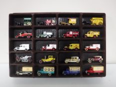 A display case containing twenty die cast vehicles, Matchbox, Days Gone By, delivery vans,
