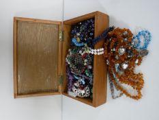 A wooden box of costume jewellery - necklaces and beads etc.