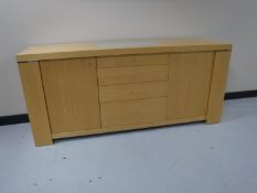 A contemporary beech sideboard with inset glass panel top