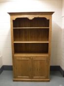 A pine bookcase fitted with cupboards below,