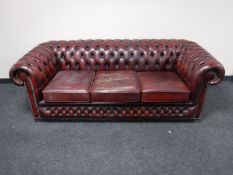 An oxblood button leather Chesterfield three seater settee and wingback armchair