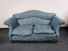 A late Victorian scroll arm settee upholstered in a purple and gold fabric on claw and ball feet