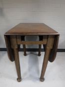 An antique oak gate leg table on club feet