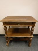 An early twentieth century oak two tier stand, fitted with a drawer,
