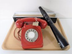 A tray containing a red plastic cased telephone,