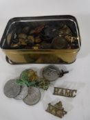 A tin containing assorted cap badges, trench art cap, military buttons,