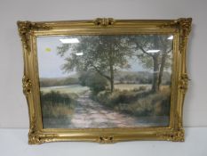 A gilt framed colour print depicting a woodland track