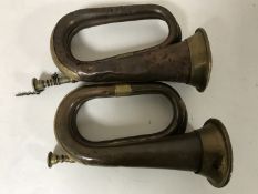 Two copper and brass bugles together with a swagger stick