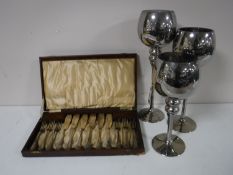 Three glass goblets together with a case of cutlery